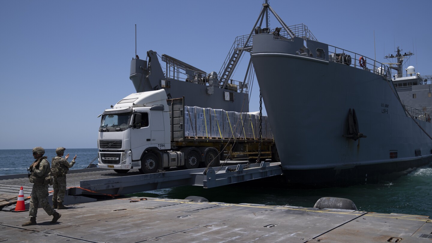 A U.S. Army soldier gestures as trucks loaded with humanitarian aid arrive at the U.S.-built floating pier Trident before reaching the beach on the co