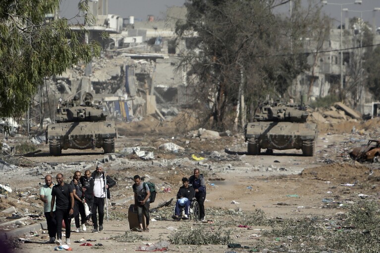 CORRECTS DIRECTION TO FLEE FROM - FILE - Palestinians flee from northern Gaza as Israeli tanks block the Salah al-Din road in the central Gaza Strip on Nov. 24, 2023, as the four-day cease-fire in the Israel-Hamas war begins as part of an agreement that Qatar helped broker. (AP Photo/Mohammed Dahman, File)