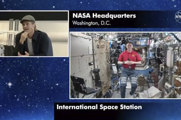 In this image taken from NASA video actor Brad Pitt, left, star of the new space movie “Ad Astra,” speaks from NASA headquarters in Washington, to astronaut Nick Hague abroad the International Space Station, on Monday, Sept. 16, 2019. (NASA via AP)