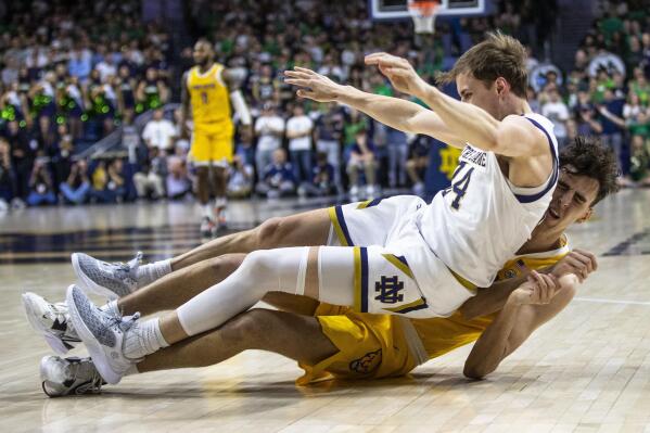 Notre Dame's Robby Carmody (24) falls onto Pittsburgh's Guillermo Diaz Graham during the first half of an NCAA college basketball game Wednesday, March 1, 2023, in South Bend, Ind. (AP Photo/Michael Caterina)
