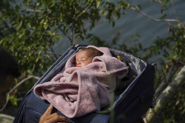 Migrants cross the Rio Grande into the U.S. with a baby in a suitcase, as seen from Matamoros, Mexico, Wednesday, May 10, 2023. Asylum seekers have been showing up at the US-Mexico border in huge numbers in anticipation of the restriction of Title 42, that had allowed the government to quickly expel migrants to Mexico. New measures were announced Wednesday creating new legal pathways for migrants. (AP Photo/Fernando Llano)