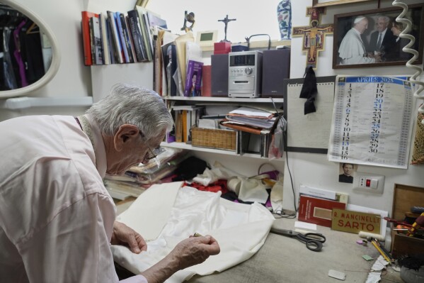 Italian tailor Raniero Mancinelli. who on his own initiative is making outfits for a possible future Pope, works on a pontiff's robe inside his shop in Rome, Wednesday, April 30, 2025. (AP Photo/Gregorio Borgia)