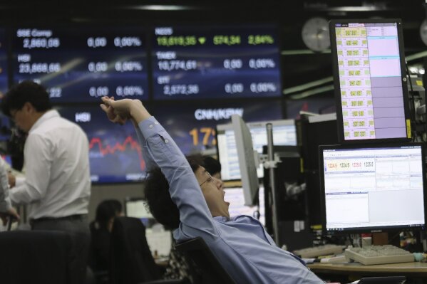 A currency trader stretches at the foreign exchange dealing room of the KEB Hana Bank headquarters in Seoul, South Korea, Wednesday, May 6, 2020. Asian stock markets were mixed Wednesday as hopes for a global economic recovery rose after more governments eased anti-virus controls. (AP Photo/Ahn Young-joon)