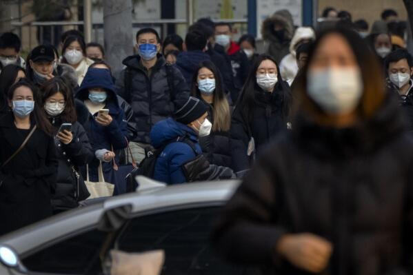 Commuters wearing face masks walk along a street during the morning rush hour in the central business district in Beijing, Thursday, Feb. 16, 2023. (AP Photo/Mark Schiefelbein)
