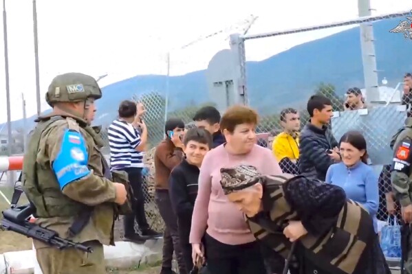 In this photo taken from video released by Russian Defense Ministry Press Service on Thursday, Sept. 21, 2023, Russian peacekeepers guard a gate into a camp near Stepanakert in Nagorno-Karabakh. Thousands of Nagorno-Karabakh residents flocked to a camp operated by Russian peacekeepers to avoid the fighting, while many others gathered at the airport of the regional capital, Stepanakert, hoping to flee the region. (Russian Defense Ministry Press Service via AP)