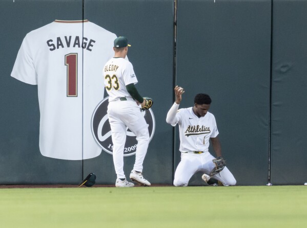 Athletics outfielder Denzel Clarke holds the ball up after colliding into the wall during the fourth inning of a baseball game against the Baltimore Orioles Friday, June 6, 2025, in West Sacramento, Calif. (AP Photo/Sara Nevis)