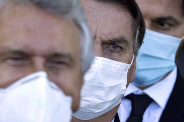 Brazilian President Jair Bolsonaro, center, arrives for a press conference following a meeting about the federal government's response to the COVID-19 pandemic at the presidential residence Alvorada Palace in Brasilia, Brazil, Wednesday, March 24, 2021. In recent weeks, Latin America’s largest country has become the pandemic’s global epicenter, with more deaths from the virus each day than in any other nation. (AP Photo/Eraldo Peres)