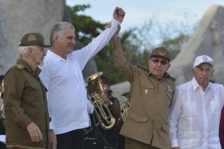 FILE - In this July 26, 2019 file photo, Cuba's President Miguel Diaz-Canel, second left, and former President Raul Castro, raise their arms in unison during an event celebrating Revolution Day, accompanied by Commander of the Cuban Revolution Ramiro Valdes, left, and Jose Ramon Machado Ventura, second secretary of the Central Committee, in Bayamo, Cuba. Cuba’s top legislative body will no longer include members of the country’s historical generation of former rebels, part of a broader political reform that started to go into effect on Thursday, Oct. 10, 2019. (Omara Garcia/Agencia Cubana de Noticias via AP File)