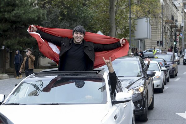 Azerbaijani man with the national flag celebrates after the country's President claimed Azerbaijani forces have taken Shushi, a key city in the Nagorno-Karabakh region that has been under the control of ethnic Armenians for decades in Baku, Azerbaijan, Sunday, Nov. 8, 2020. (AP Photo)
