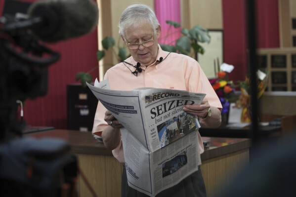 Editor and Publisher Eric Meyer goes through the latest edition of his newspaper, the Marion County Record, during a news conference about the aftermath of a raid on its offices and his home by local police, Wednesday, Aug. 18, 2023, at its offices in Marion, Kan. The local prosecutor and Kansas Bureau of Investigation say computers and personal cell phones seized in the raids are being returned. (AP Photo/John Hanna)