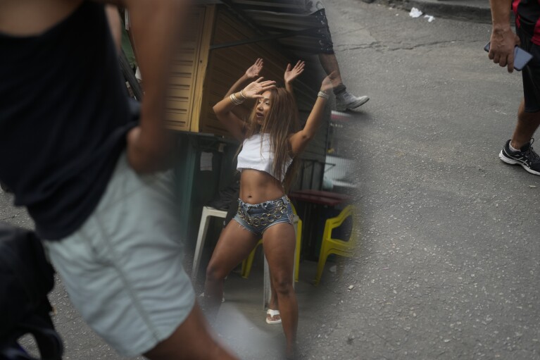 FILE - Reflected in a motorcycle side mirror, a woman performs a street dance style known as passinho, in the Rocinha favela of Rio de Janeiro, Brazil, April 11, 2024. Passinho or "little step" began with small groups performing at parties inside Rio's favelas, but has since spread, helping to break the stigma of the communities often known for violence and drug gangs. (AP Photo/Silvia Izquierdo, File)