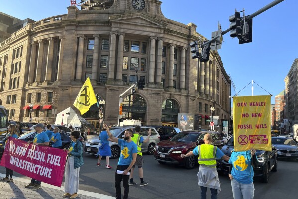 Climate activists display banners as they block traffic, Thursday, Sept. 21, 2023, at South Station, in Boston. The demonstrators briefly disrupted the morning commute Thursday near the train station to put pressure on the state's governor to ban fossil fuel infrastructure. (Kevin Martin/The Boston Globe via AP)