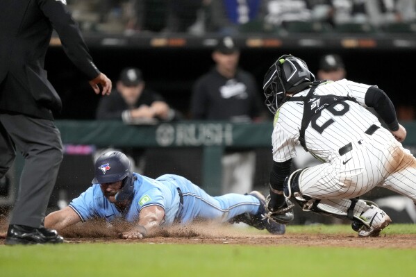 Toronto Blue Jays' Davis Schneider, left, scores next to Chicago White Sox catcher Korey Lee during the eighth inning of a baseball game Tuesday, May 28, 2024, in Chicago. (AP Photo/Charles Rex Arbogast)