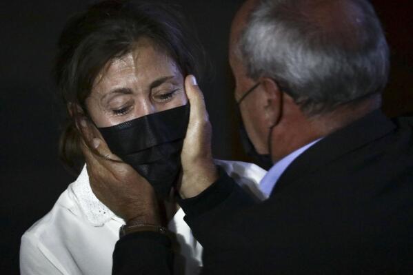 Former Colombian Presidential candidate Ingrid Betancourt, left, who was abducted while campaigning by the Revolutionary Armed Forces of Colombia, FARC,  rebels, is comforted by another kidnapping victim during an event at the Truth Commission to commemorate victims of the country’s decades long armed conflict, in Bogota, Colombia, Wednesday, June 23, 2021. (AP Photo/Ivan Valencia)