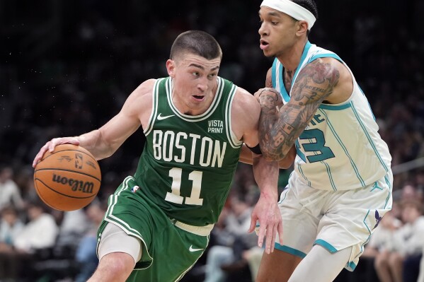 Boston Celtics' Payton Pritchard (11) drives past Charlotte Hornets' Tre Mann (23) during the second half of an NBA basketball game, Friday, April 12, 2024, in Boston. (AP Photo/Michael Dwyer)