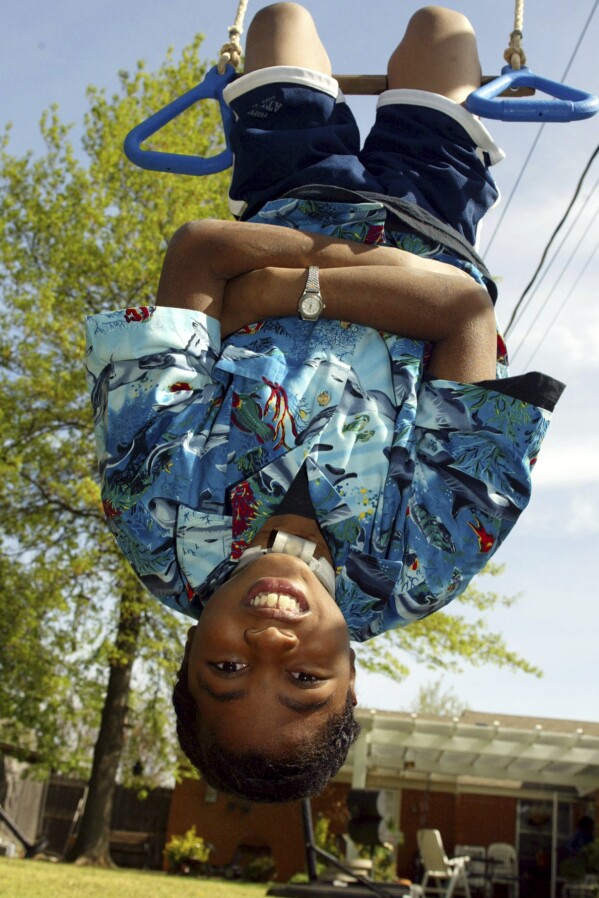 Nine-year-old P.J. Allen plays in his backyard in Oklahoma City on April 17, 2003. One of the youngest survivors of the Oklahoma City bombing, Allen says he wants more than anything to be able to swim and wrestle with his friends without worrying about the tracheotomy in his throat getting dislodged. (AP Photo/Sue Ogrocki, File)