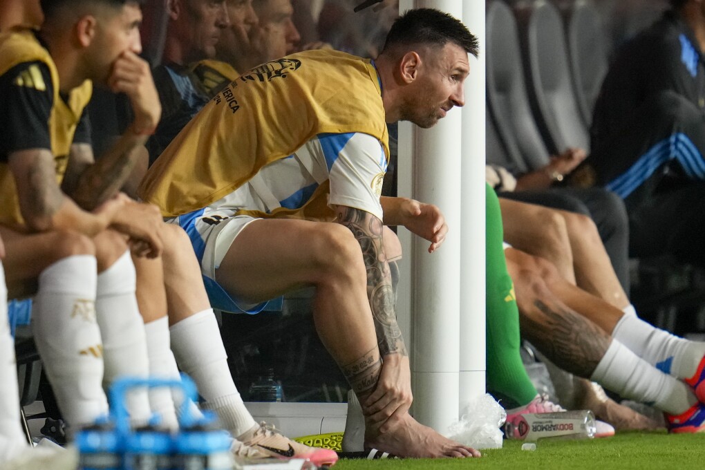 Argentina's Lionel Messi touches his ankle sitting at the bench during a Copa America soccer final match against Colombia in Miami Gardens, Fla., Sunday, July 14, 2024. (AP Photo/Julio Cortez)