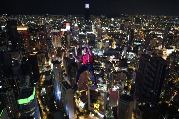 A base jumper dives at night from the Kuala Lumpur Tower during KL Tower International Jump in Kuala Lumpur, Malaysia, Saturday, Feb. 4, 2023. (AP Photo/Vincent Thian)