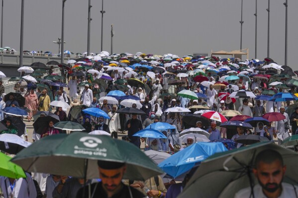 FILE - Muslim pilgrims use umbrellas to protect themselves from the sun as they arrive to throw stones at pillars in the symbolic stoning of the devil, the last ritual of the annual Hajj, in Mina, near the holy city of Mecca, Saudi Arabia, Tuesday, June 18, 2024. Sunday, June 23, 2024 More than 1,000 people died during this year’s Hajj season in Saudi Arabia as believers faced extremely high temperatures in Islamic holy sites in the desert kingdom.  (AP Photo/Rafiq Maqbool)