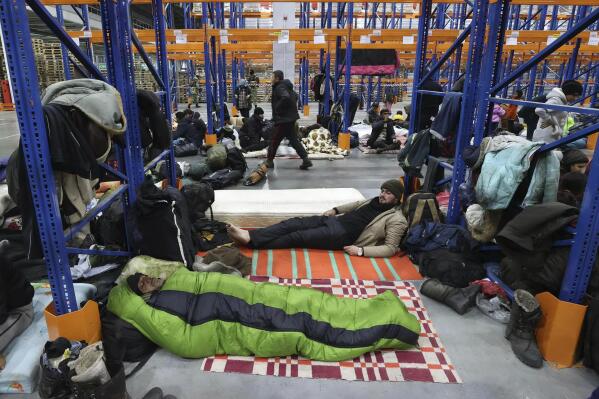 Migrants settle for the night in the logistics center in the checkpoint "Kuznitsa" at the Belarus-Poland border near Grodno, Belarus, on Tuesday, Nov. 16, 2021. Some of the migrants have children with them at the border in their desperate bid to reach the EU. Most are fleeing conflict, poverty and instability in the Middle East and elsewhere. (Maxim Guchek/BelTA via AP)