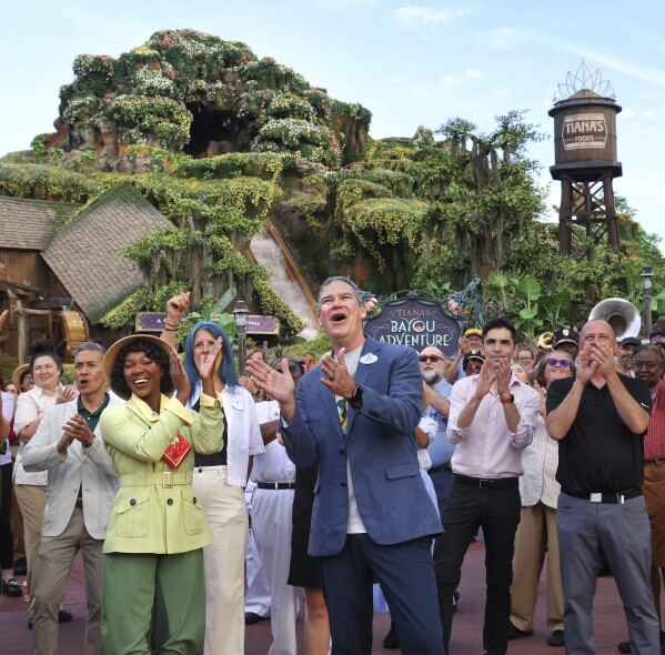 With Princess Tiana, Walt Disney World president Jeff Vahle cheers employees during a "Thank You Fête" honoring cast members at a preview event for Tiana's Bayou Adventure at the Magic Kingdom in Bay Lake, Fla., Monday, June 10, 2024. The ride —redeveloped from the park's original Splash Mountain— officially opens to Disney guests on June 28. (Joe Burbank/Orlando Sentinel via AP)