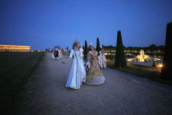 Costumed guests run in the gardens of the Versailles castle before the Great Masked Ball in Versailles, outside Paris, Saturday, June 21, 2025. (AP Photo/Christophe Ena)