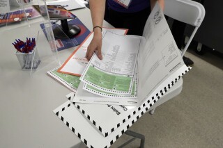 FILE - A poll worker assembles a ballot at Frank McCourt High School in New York's party primaries, Tuesday, June 22, 2021, in New York. Some online are claiming that COVID-19 only spikes during election seasons, but experts say there is no connection between the two. (AP Photo/Richard Drew)