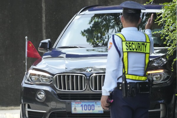 FILE - A security guard signals to a car with diplomatic plates and Chinese flag as he parks at the Philippine Department of Foreign Affairs in Manila, Philippines on Aug. 7, 2023. A top Philippine security official demanded Friday May 10, 2024 the immediate expulsion of Chinese diplomats who reportedly leaked an alleged phone conversation between an embassy official and a Filipino admiral about handling the South China Sea territorial rifts, which have escalated and strained relations. (AP Photo/Aaron Favila, File)