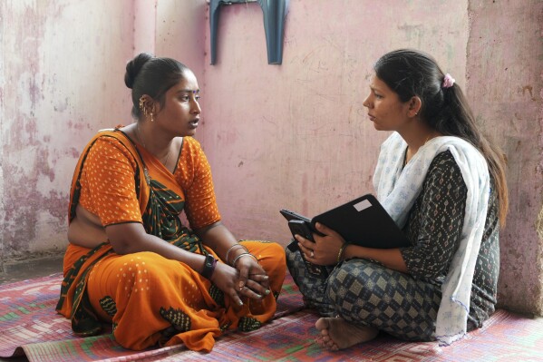 Data collector Komal Parmar, right, talks with Sapnaben Chunara to get heat related information in Ahmedabad, India, Wednesday, April 2, 2025. (AP Photo/Ajit Solanki)