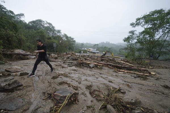 A man crosses a highway blocked by a landslide triggered by Hurricane Otis near Acapulco, Mexico, Wednesday, Oct. 25, 2023. The hurricane turned from mild to monster in record time, and scientists are struggling to figure out how — and why they didn't see it coming. (AP Photo/Marco Ugarte)
