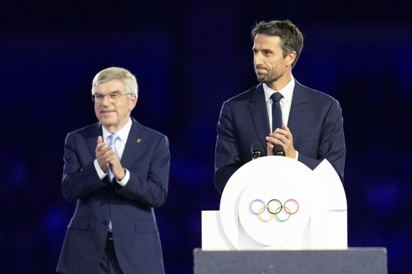 President of the Paris 2024 Organizing Committee, Tony Estanguet, right, addresses the audience as and IOC President Thomas Bach watches during the 2024 Summer Olympics closing ceremony at the Stade de France, Sunday, Aug. 11, 2024, in Saint-Denis, France. (AP Photo/Ashley Landis)