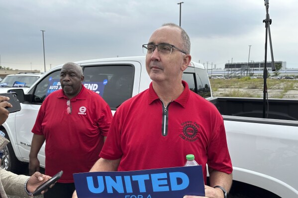 FILE - United Auto Workers President Shawn Fain holds up a sign at a union rally held near a Stellantis factory Wednesday, Aug. 23, 2023, in Detroit. The demands that a more combative United Auto Workers union has made of General Motors, Stellantis and Ford — demands that even the UAW's president has called “audacious” — are edging it closer to a strike when its current contract ends Sept. 14. (AP Photo/Mike Householder, File)