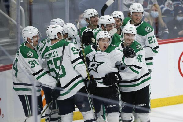 Dallas Stars' Jason Robertson (21), center, and teammates celebrates his overtime goal against the Winnipeg Jets in an NHL hockey game Friday, March 4, 2022, in Winnipeg, Manitoba. (John Woods/The Canadian Press via AP)