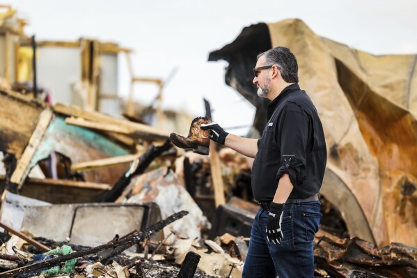 Sen. Ted Cruz, R-Texas, holds up a small cowboy boot he recovered from debris in a trailer park that was damaged by a tornado earlier in Perryton, Texas, Saturday, June, 17, 2023. (AP Photo/David Erickson)