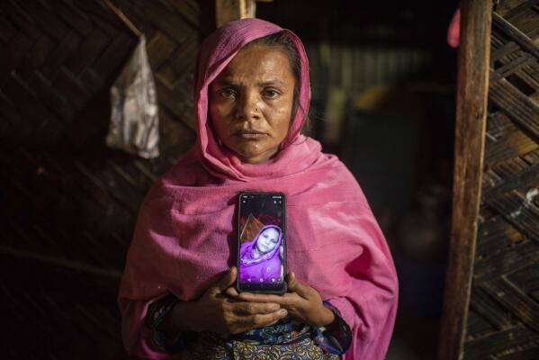 Hasina Khatun shows a photo of her 18-year-old daughter, Asma Bibi, who was 9-months pregnant when she and her little brother fled the Rohingya refugee camps in December 2022 and boarded a boat bound for Indonesia, during an interview in the Nayapara refugee camp in Teknaf, part of the Cox's Bazar district of Bangladesh, on March 10, 2023. The boat, which was carrying around 180 Rohingya refugees, disappeared a week into its journey. (AP Photo/Mahmud Hossain Opu)