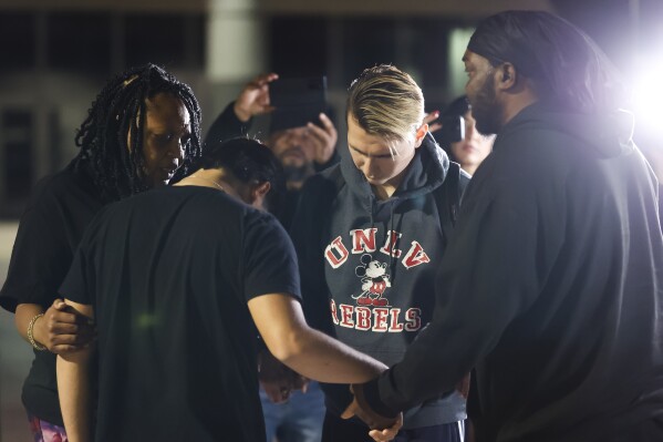 University of Nevada, Las Vegas, student Carlos Casillas, 23, second from right, prays at the Las Vegas Convention Center reunification area where he was transported after a fatal shooting at the campus in Las Vegas, Wednesday, Dec. 6, 2023. (Wade Vandervort/Las Vegas Sun via AP)