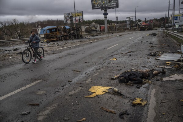 FILE - EDS NOTE: GRAPHIC CONTENT - A woman walks next to a dead Russian soldier in Bucha, in the outskirts of Kyiv, Ukraine, Saturday, April 2, 2022. Nearly 50,000 Russian soldiers have died in the war in Ukraine, according to a new statistical analysis. (AP Photo/Rodrigo Abd)