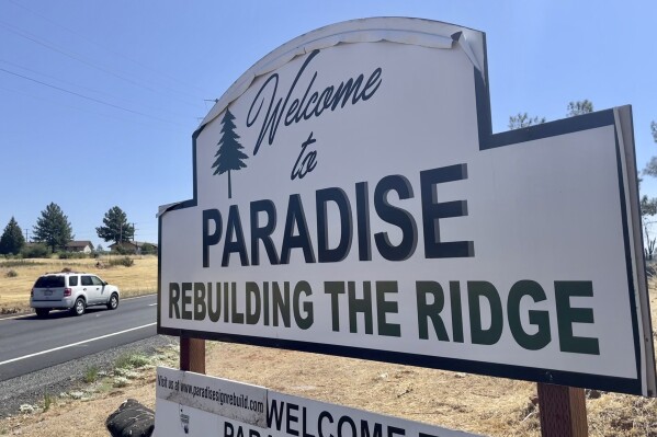A sign welcomes motorists to Paradise, Calif., on Saturday, Aug. 5, 2023. Officials in Paradise, California, began testing a new wildfire siren system this summer as the five-year anniversary of the deadly and devastating Camp Fire approaches. Reliable warning systems are becoming more critical during wildfires, especially as power lines and cell towers fail, knocking out communications critical to keeping people informed. (AP Photo/Haven Daley)