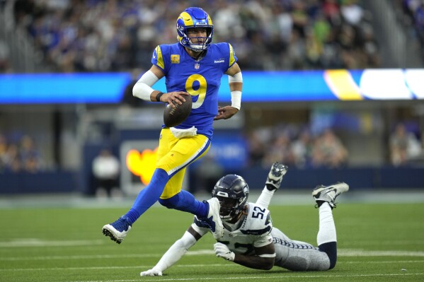 Los Angeles Rams quarterback Matthew Stafford (9) runs the ball after evading a tackle from Seattle Seahawks linebacker Darrell Taylor (52) during the second half of an NFL football game Sunday, Nov. 19, 2023, in Inglewood, Calif. (AP Photo/Ashley Landis)