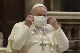 FILE - In this Oct. 20, 2020, file photo, Pope Francis puts on his face mask as he attends an inter-religious ceremony for peace in the Basilica of Santa Maria in Aracoeli, in Rome. Pope Francis has been warned of potential exposure to COVID-19 after a Vatican diplomat was infected, Australian media reported on Friday, Oct. 23, 2020. Archbishop Adolfo Tito Yllana, the Holy See’s ambassador to Australia, had a face-to-face meeting with Francis at the Vatican on Oct. 6, less than two weeks before testing positive to COVID-19 in Australia, Nine News reported. (AP Photo/Gregorio Borgia)