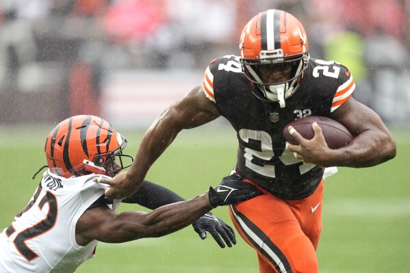 Cleveland Browns running back Nick Chubb (24) is grabbed by Cincinnati Bengals cornerback Chidobe Awuzie (22) on a run during the first half of an NFL football game Sunday, Sept. 10, 2023, in Cleveland. (AP Photo/Sue Ogrocki)