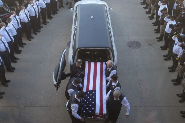The casket of Santaquin Police Sgt. Bill Hooser arrives at Utah Valley University Monday, May 13, 2024, in Orem, Utah. Hooser was killed on May 5, 2024, while helping a Utah Highway Patrol trooper with a traffic stop when police say a man driving a semi-trailer intentionally hit Hooser. (AP Photo/Rick Bowmer)
