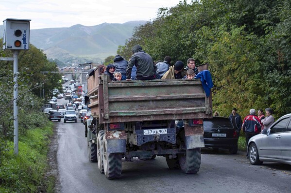 Ethnic Armenians fleeing Nagorno-Karabakh travel in the bed of a dump truck to Goris, in Armenia's Syunik region, Tuesday, Sept. 26, 2023. (AP Photo/Gaiane Yenokian)