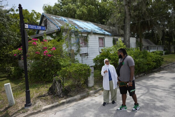 NY Nathiri, left, and Julian Johnson, who lead separate organizations working to preserve the town's heritage and culture, and boost its economy, talk together as they walk past the town's oldest remaining structure, known as the Historic Thomas House, in Eatonville, Fla., Wednesday, Aug. 23, 2023. Historic Black communities have dwindled from their once-thriving existence in the United States and efforts to preserve what's left encounter complicated challenges. (AP Photo/Rebecca Blackwell)