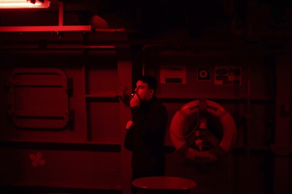 A French sailors smokes a cigarette on board of the French navy frigate Normandie during a patrol in a Norwegian fjord, north of the Arctic circle, Thursday March 7, 2024. The French frigate is part of a NATO force conducting exercises in the seas, north of Norway, codenamed Steadfast Defender, which are the largest conducted by the 31 nation military alliance since the cold war. (AP Photo/Thibault Camus)