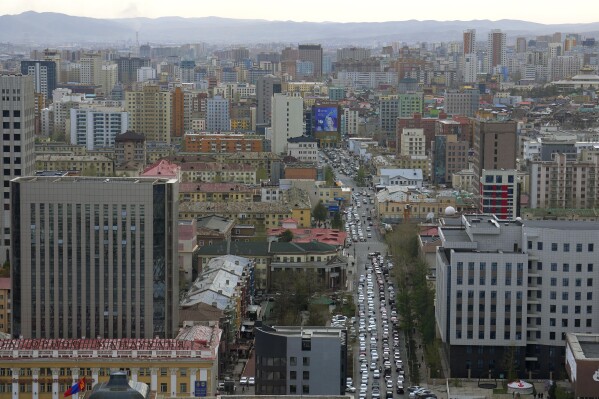 Traffic crawls between high rise buildings in Ulaanbaatar, the capital of Mongolia, Monday, May 22, 2023. The nation bordered by China and Russia is known for vast, rugged expanses and nomadic culture. (AP Photo/Manish Swarup)