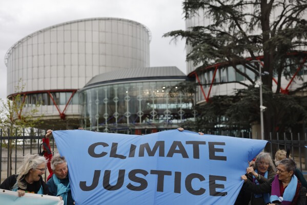 People demonstrate outside the European Court of Human Rights Tuesday, April 9, 2024 in Strasbourg, eastern France. Europe's highest human rights court will rule Tuesday on a group of landmark climate change cases aimed at forcing countries to meet international obligations to reduce greenhouse gas emissions. The European Court of Human Rights will hand down decisions in a trio of cases brought by a French mayor, six Portuguese youngsters and more than 2,000 elderly Swiss women who say their governments are not doing enough to combat climate change. (AP Photo/Jean-Francois Badias)