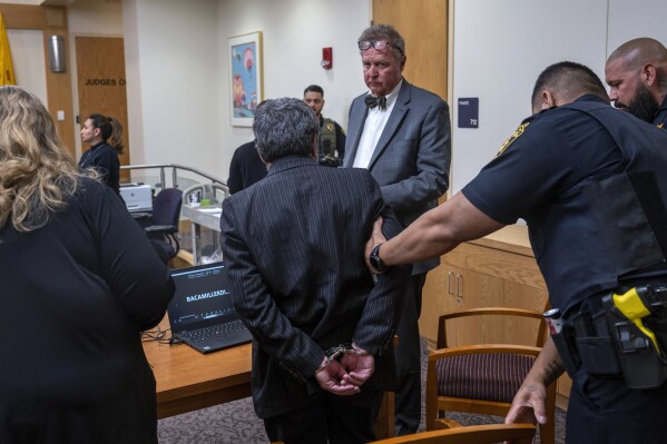 Muhammed Syed, center, with his attorney Thomas Clark, is taken into custody after he was convicted of killing Aftab Hussien in 2022, in Bernalillo County Courthouse in Albuquerque, N.M., Monday, March 18, 2024. (Eddie Moore/The Albuquerque Journal via AP)