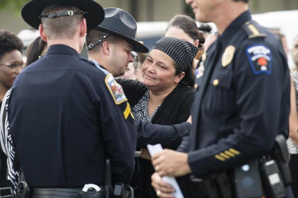 Candice Gulley is greeted by Alabama State Troopers following a prayer vigil for the eight Alabama children that died in a June 19 crash on I-65 at Church of the Highlands in Auburn, Ala., on Thursday, July 15, 2021. Gulley was the sole survivor of a passenger van that crashed June 19 that killed eight Alabama children including two of her own. (Jake Crandall/The Montgomery Advertiser via AP)
