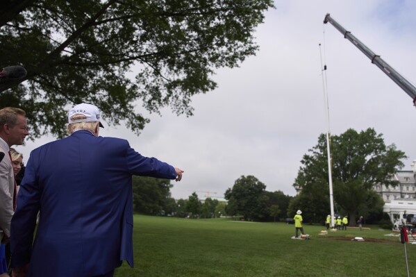 President Donald Trump speaks with reporters as a flag pole is installed on the South Lawn of the White House, Wednesday, June 18, 2025, in Washington. (AP Photo/Evan Vucci)
